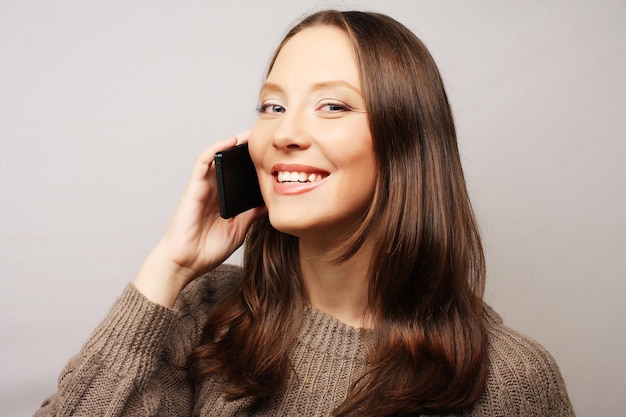 Giovane donna felice che utilizza un telefono cellulare isolato su uno sfondo bianco