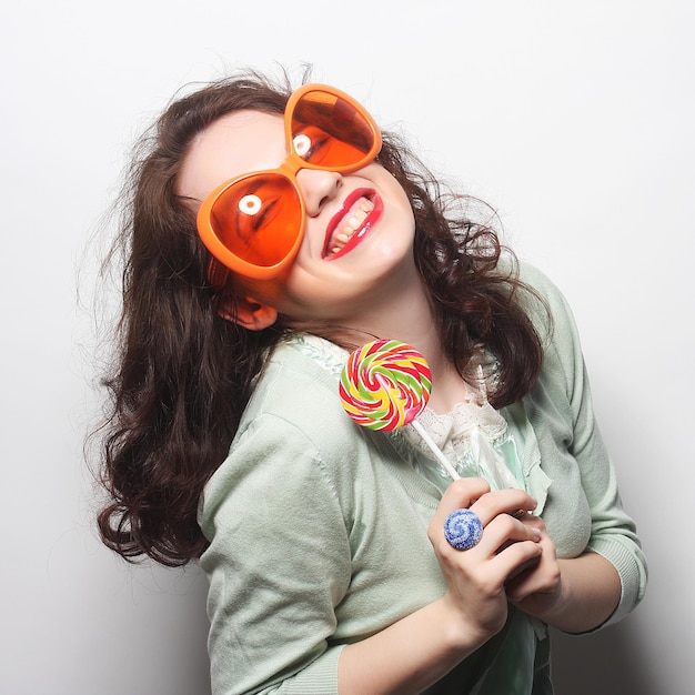 Giovane donna felice con grandi occhiali da sole arancioni