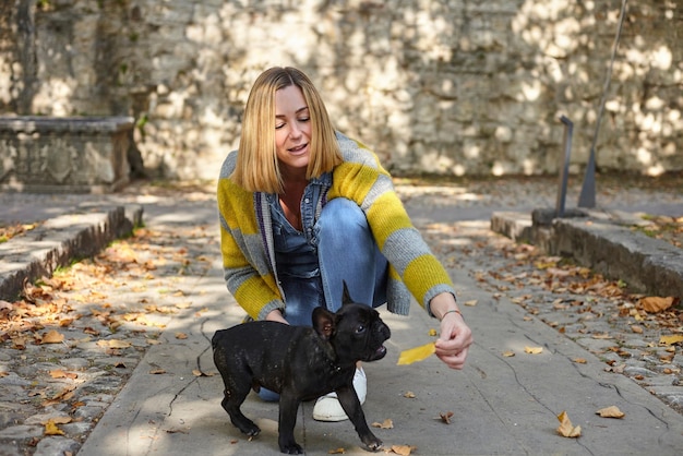 Giovane donna felice con il bulldog francese all'aperto