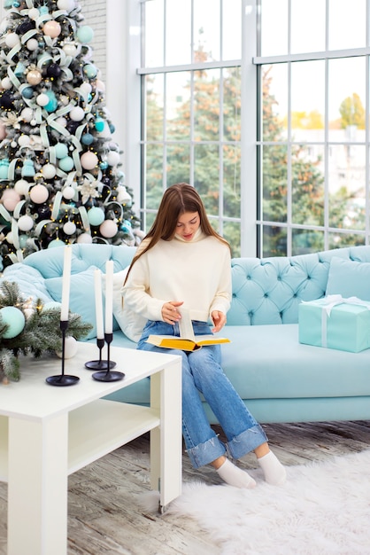 giovane donna felice con il libro a natale a casa sullo sfondo delle decorazioni natalizie