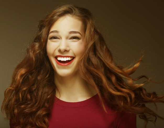 Giovane donna felice con il vento nei capelli. Colpo dello studio.