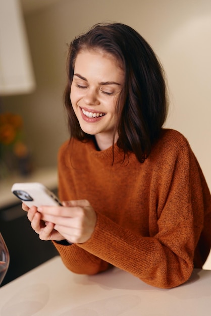 Giovane donna felice con uno smartphone che sorride e usa un'app di comunicazione online sul divano di casa