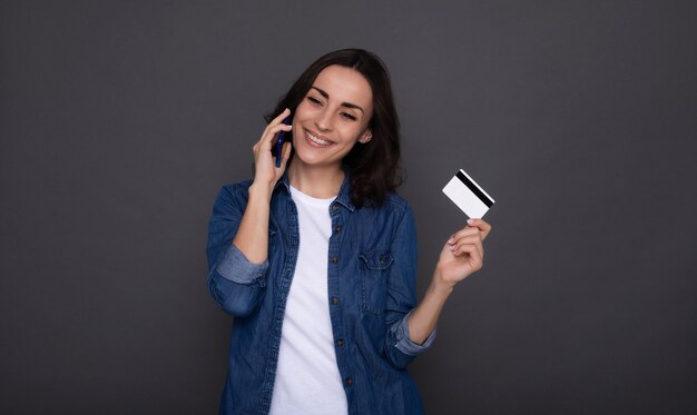 Giovane donna felice di successo con una carta di credito in mano durante lo shopping online
