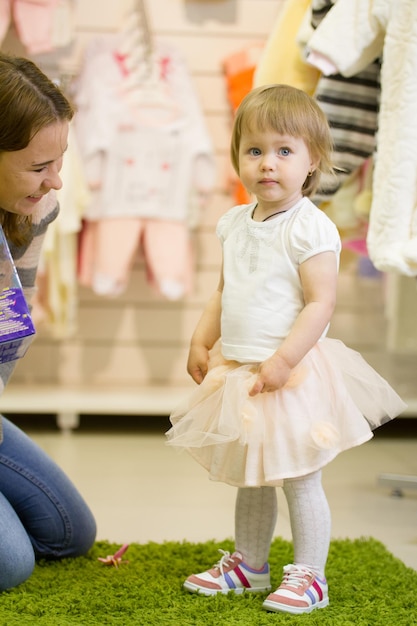 Giovane donna felice e la sua bella figlia che sorridono al negozio per bambini