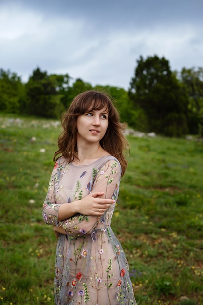 Giovane donna felice in abito lungo sulla montagna Ragazza sulla natura su sfondo azzurro del cielo Foto di moda