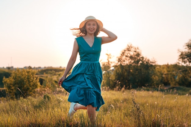 Giovane donna felice in un vestito blu nel campo estivo