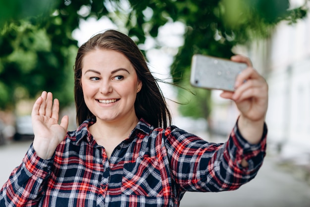 Giovane donna felice nel parco che fa selfie dalla macchina fotografica.