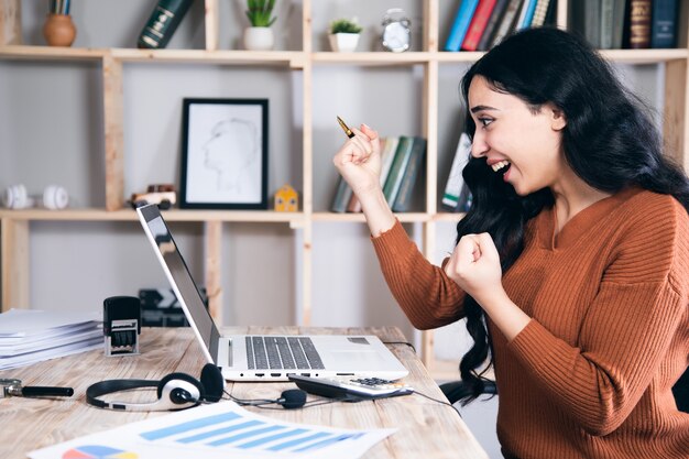 Giovane donna felice sorpresa che lavora nel computer