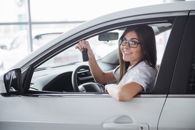 Giovane donna felice vicino all'automobile con le chiavi in mano