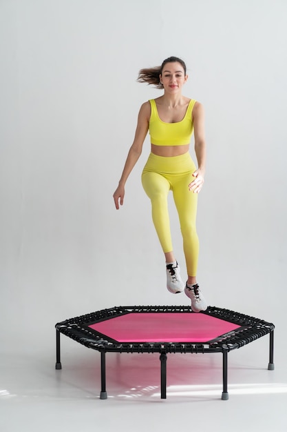 Giovane donna fitness In abbigliamento sportivo che salta sul trampolino sportivo