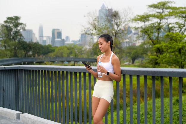 Giovane donna fitness in abbigliamento sportivo utilizzando smart phone mentre ti alleni in città