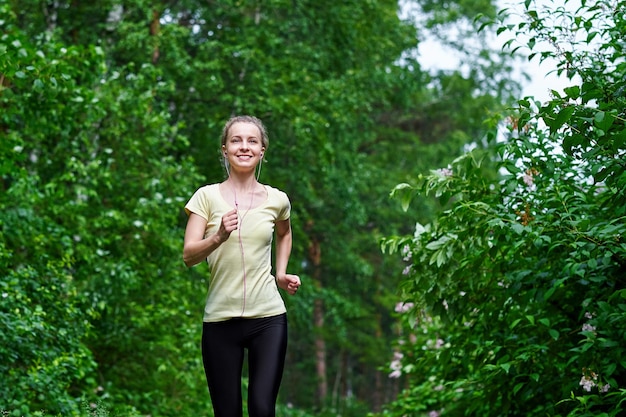 Giovane donna fitness in esecuzione al sentiero nel bosco.