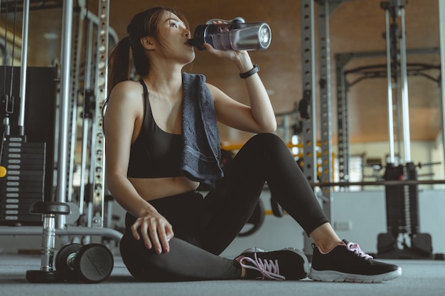 Giovane donna fitness stanca in palestra bere acqua Allenamento fitness palestra esercizio stile di vita e sano