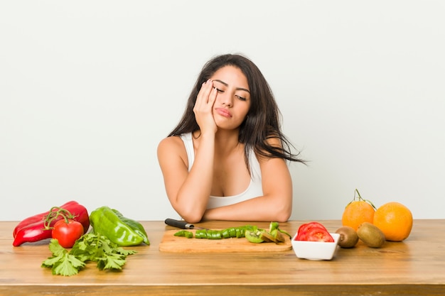 Giovane donna formosa che prepara un pasto sano che è annoiato, affaticato e ha bisogno di una giornata di relax.