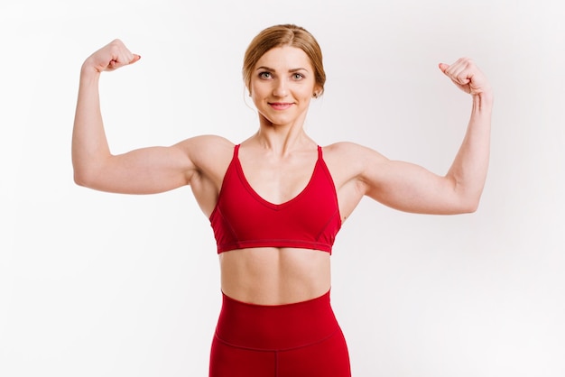 Giovane donna forte e sportiva in panno rosso su sfondo bianco