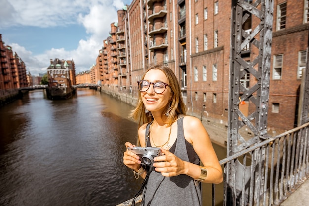 Giovane donna fotografa turistica bellissima vista sulla Speicherstadt, storico quartiere di magazzini ad Amburgo, Germany