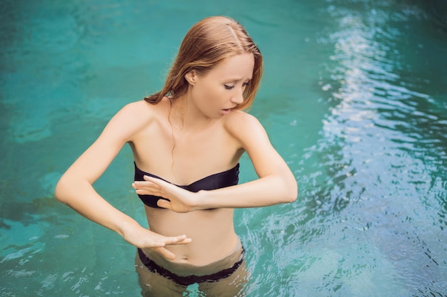 Giovane donna frustrata che ha una brutta pelle in piscina A causa del fatto che sono presenti sostanze chimiche nella piscina