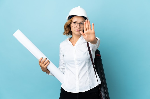 Giovane donna georgiana dell'architetto con il casco e le cianografie della holding isolate