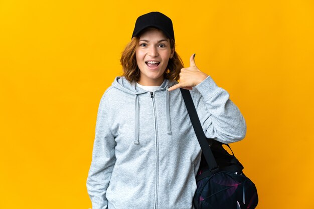 Giovane donna georgiana di sport con la borsa di sport sopra la parete isolata che fa gesto del telefono. Richiamami segno