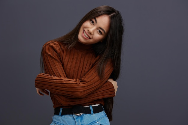 Giovane donna gesti con la mano maglione marrone emozioni di moda sfondo grigio foto di alta qualità