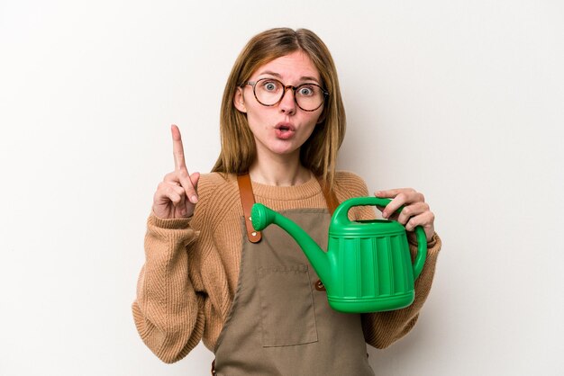 Giovane donna giardiniere in possesso di un irrigatore isolato su sfondo bianco con qualche grande idea, concetto di creatività.