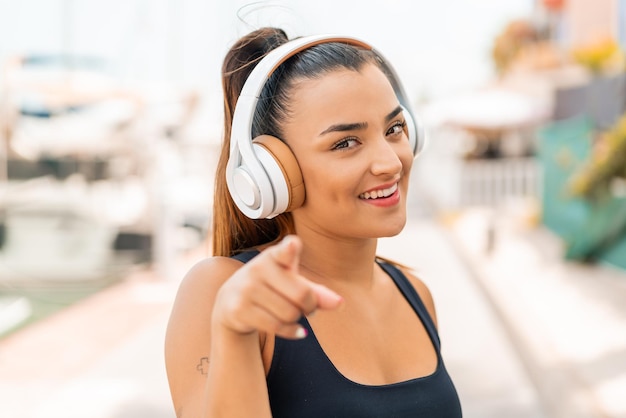 Giovane donna graziosa alla musica d'ascolto all'aperto