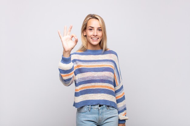 Giovane donna graziosa bionda con il maglione a strisce