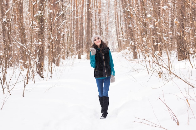 Giovane donna graziosa che cammina nel parco innevato