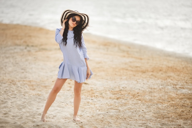 Giovane donna graziosa che cammina su una spiaggia. Ragazza adulta attraente vicino al rilassamento dell'acqua. Bella donna sul mare