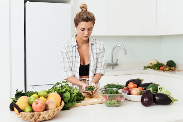 Giovane donna graziosa che cucina sano piatto vegetariano a casa