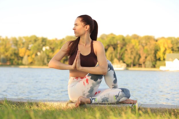 Giovane donna graziosa che fa esercizi di yoga nel parco.