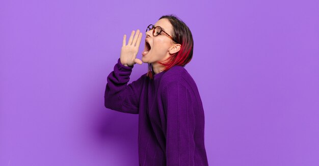 Giovane donna graziosa che gesturing sulla parete colorata