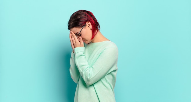 Giovane donna graziosa che gesturing sulla parete colorata