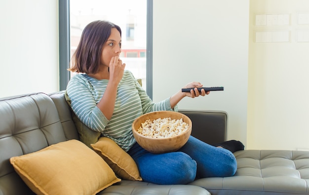 Giovane donna graziosa che guarda la tv a casa