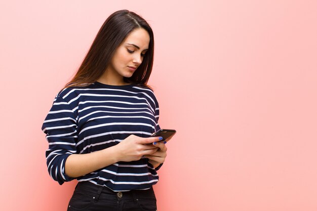 Giovane donna graziosa che per mezzo del suo telefono astuto