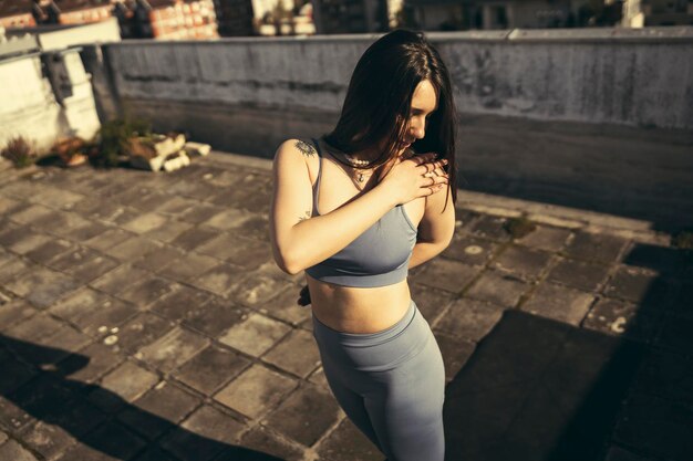 Giovane donna graziosa che pratica yoga su una terrazza sul tetto.