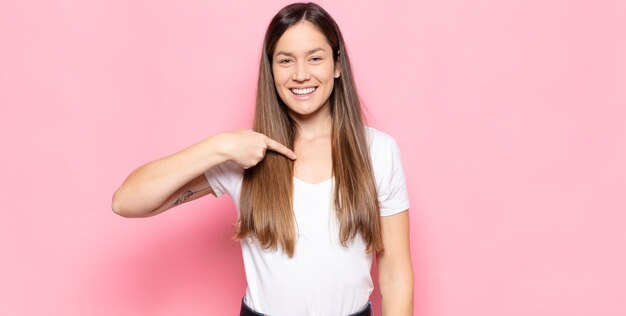 Giovane donna graziosa che sembra felice, orgogliosa e sorpresa