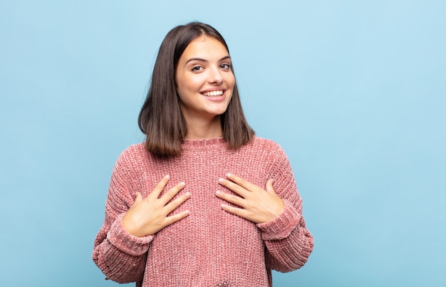 Giovane donna graziosa che sembra felice, sorpresa, orgogliosa ed emozionata, indicando se stessa