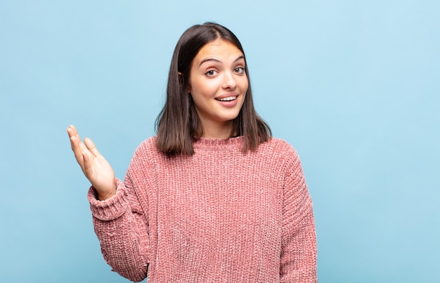 Giovane donna graziosa che si sente felice, sorpresa e allegra, sorridente con atteggiamento positivo, realizzando una soluzione o un'idea