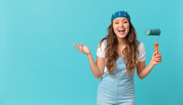 Giovane donna graziosa che si sente felice, sorpresa nel realizzare una soluzione o un'idea e dipingere un muro