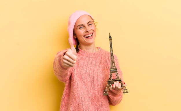 Giovane donna graziosa che si sente orgogliosa di sorridere positivamente con i pollici in su al concetto di Parigi