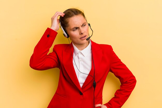 Giovane donna graziosa che si sente perplessa e confusa che graffia il concetto di telemarketing della testa