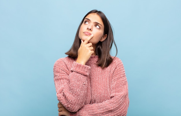 Giovane donna graziosa che si sente premurosa, chiedendosi o immaginando idee