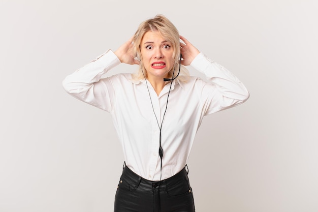 Giovane donna graziosa che si sente stressata, ansiosa o spaventata, con le mani sulla testa. concetto di telemarketing