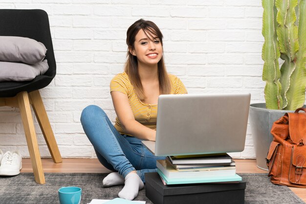 Giovane donna graziosa che si siede sul pavimento all&#39;interno