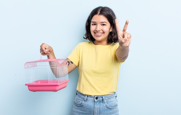 Giovane donna graziosa che sorride e che sembra amichevole che mostra il concetto della gabbia dell'animale domestico numero due