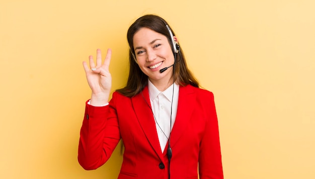 Giovane donna graziosa che sorride e che sembra amichevole che mostra il concetto di telemarketing numero quattro