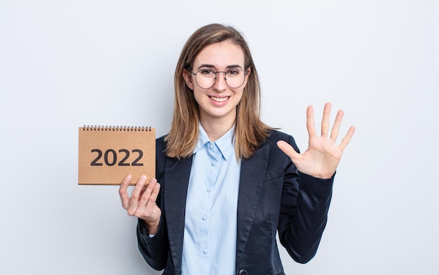 Giovane donna graziosa che sorride e che sembra amichevole, mostrando il numero cinque. concetto di calendario