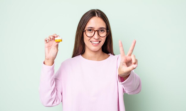 Giovane donna graziosa che sorride e sembra felice, gesticolando vittoria o pace. concetto di lenti a contatto