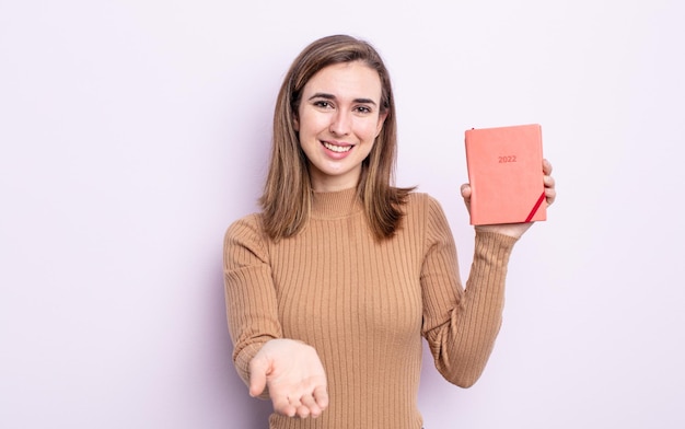 Giovane donna graziosa che sorride felicemente con amichevole e offrendo e mostrando un concetto. concetto di agenda